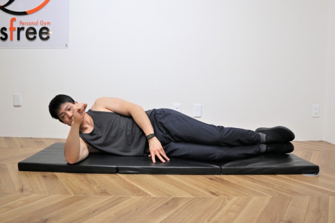 背筋を鍛える際の三角筋後部を鍛えるサイドライズの動作　１．横向きに寝転び肘を地面につける。
