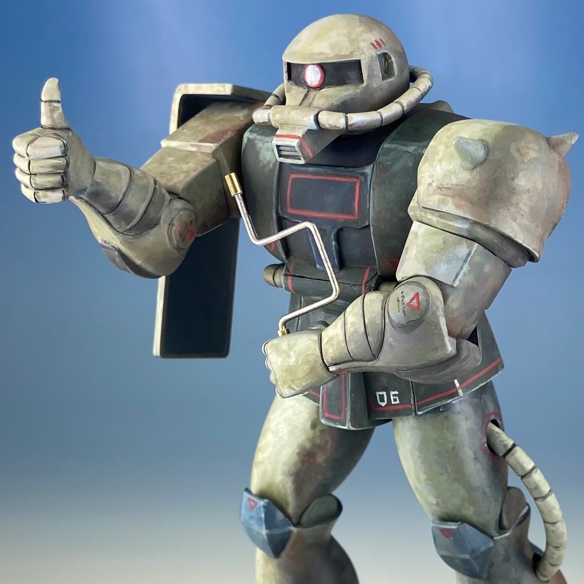 これは…“あのザク”!!」ガンプラ箱絵の片隅に描かれたサムアップ姿を